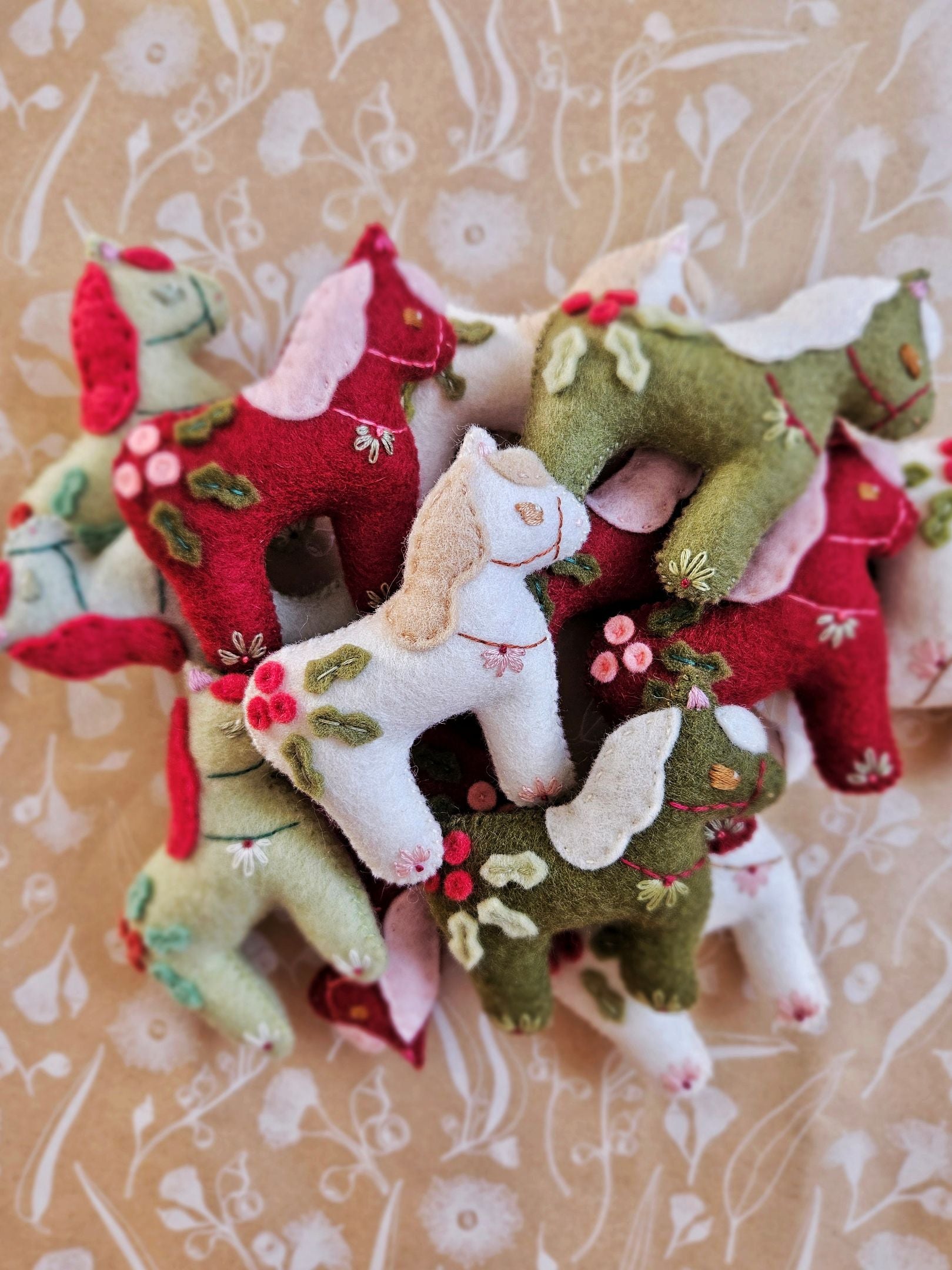 Felt ornaments shaped like animals on a floral-patterned background