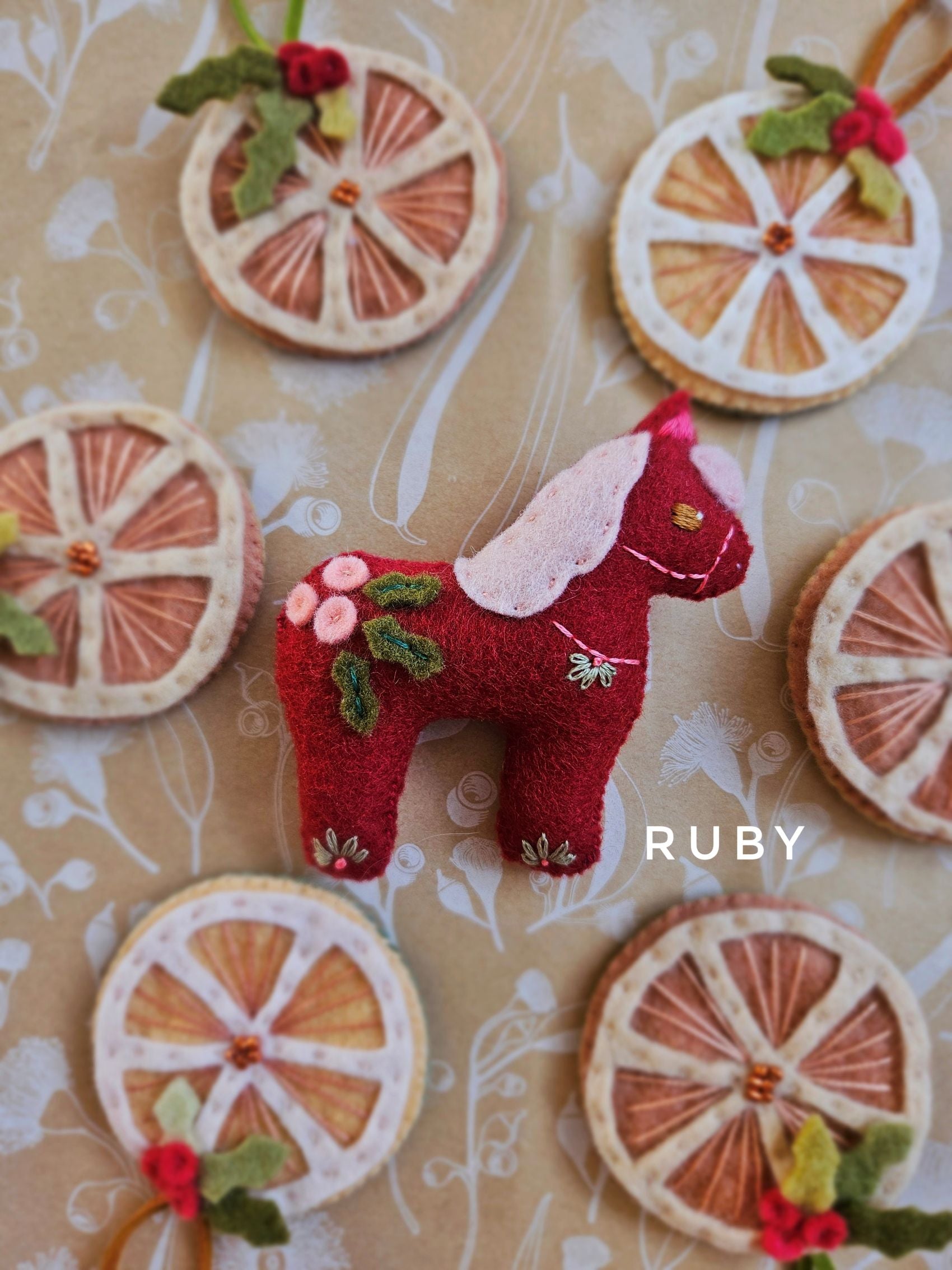 Red felt horse ornament with floral details on a patterned background