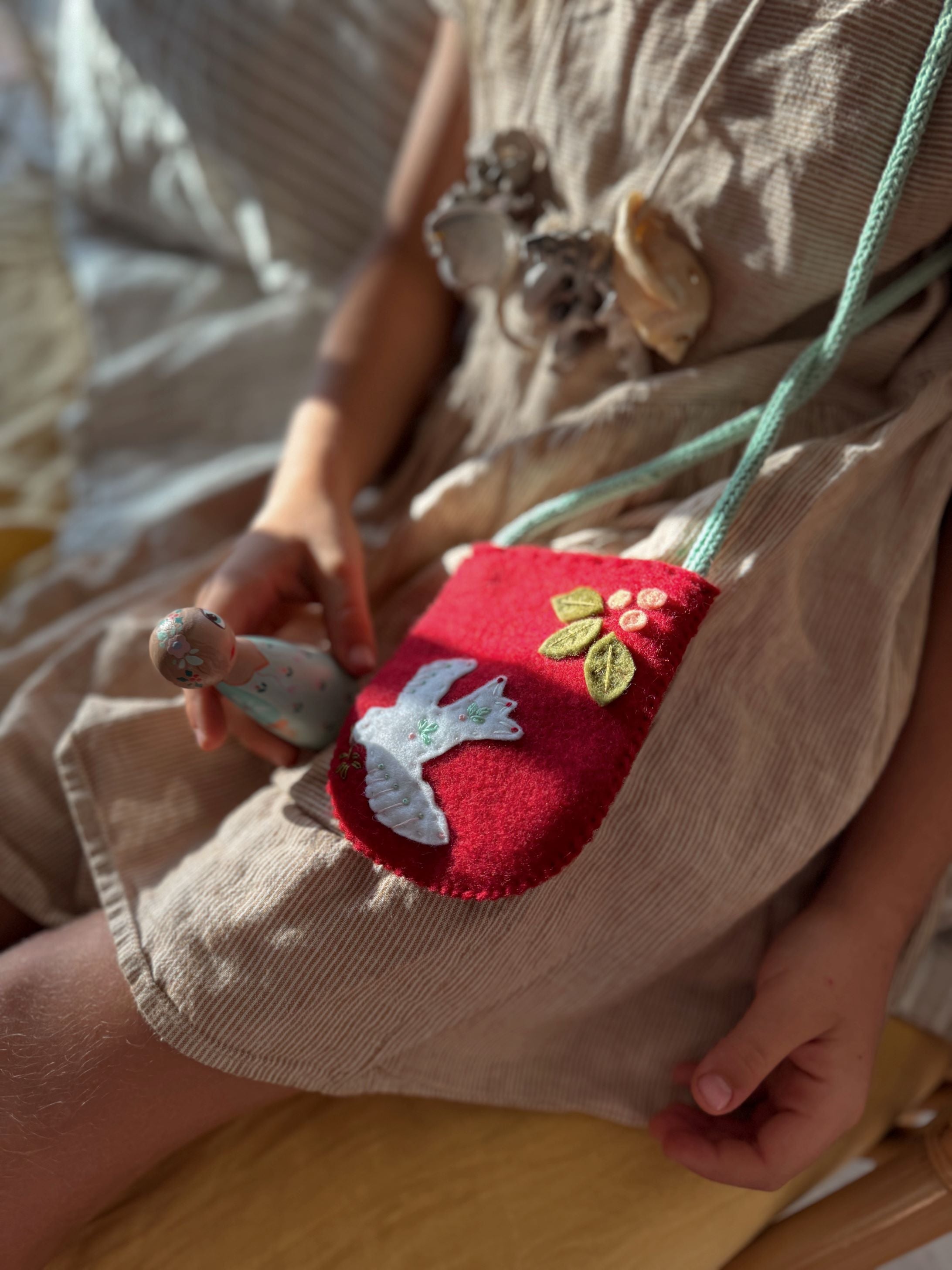 A child holding a red Christmas themed wool felt bag