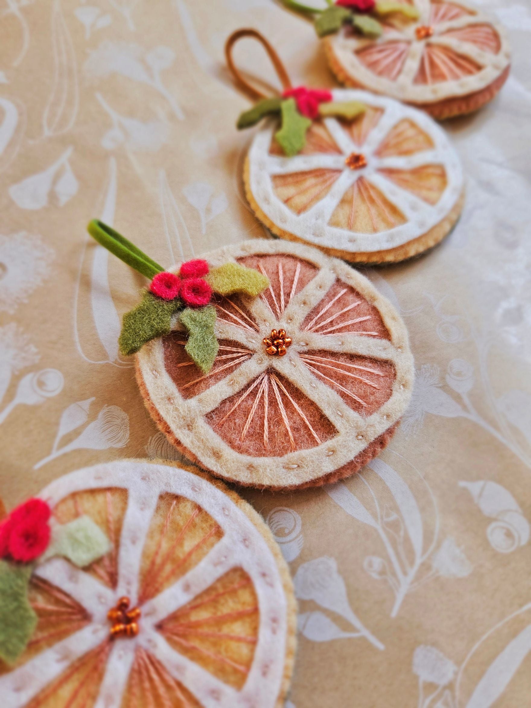 Decorative orange slices with floral and berry accents on a patterned background