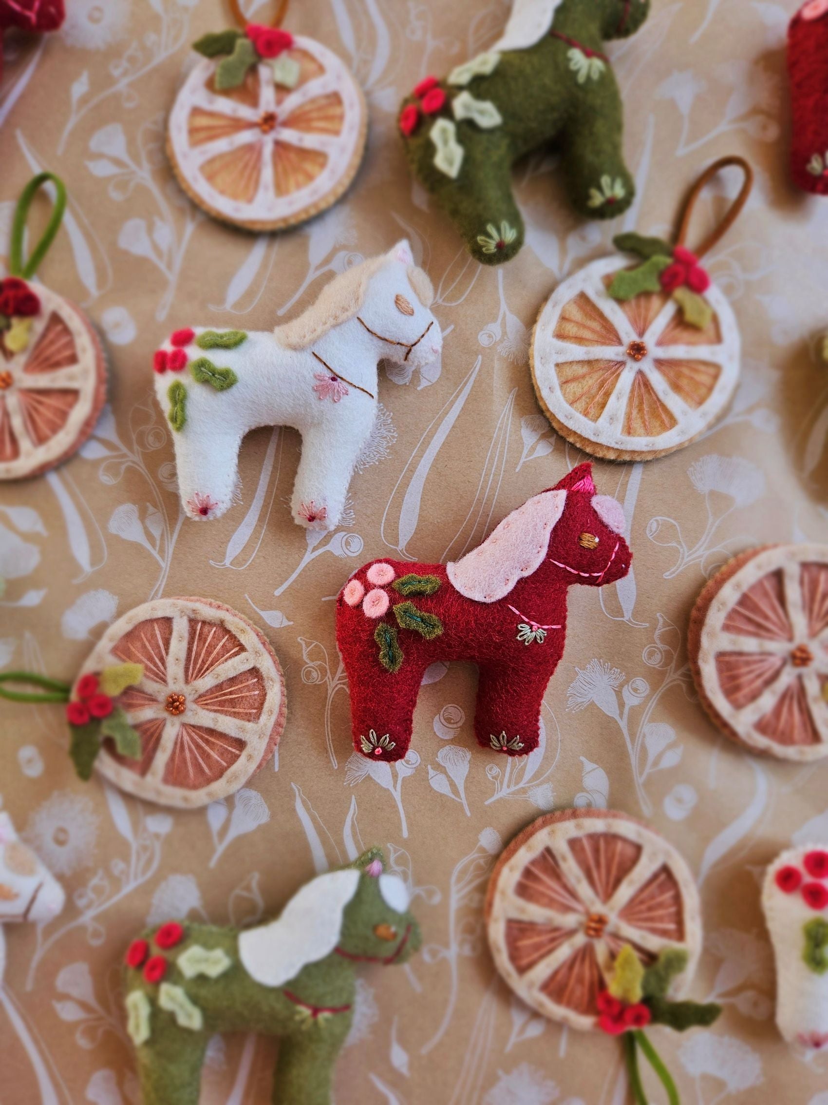 Felt horse toys and decorative wheels on a patterned background