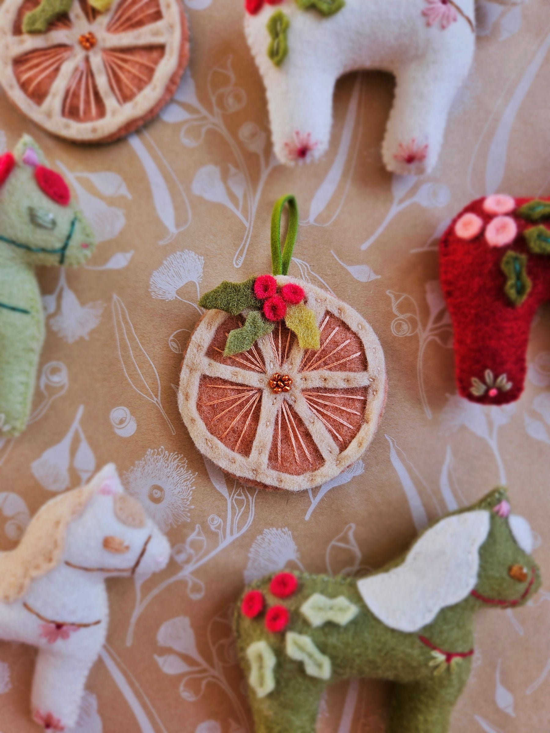 Decorative felt animals and fruit ornaments on a patterned surface