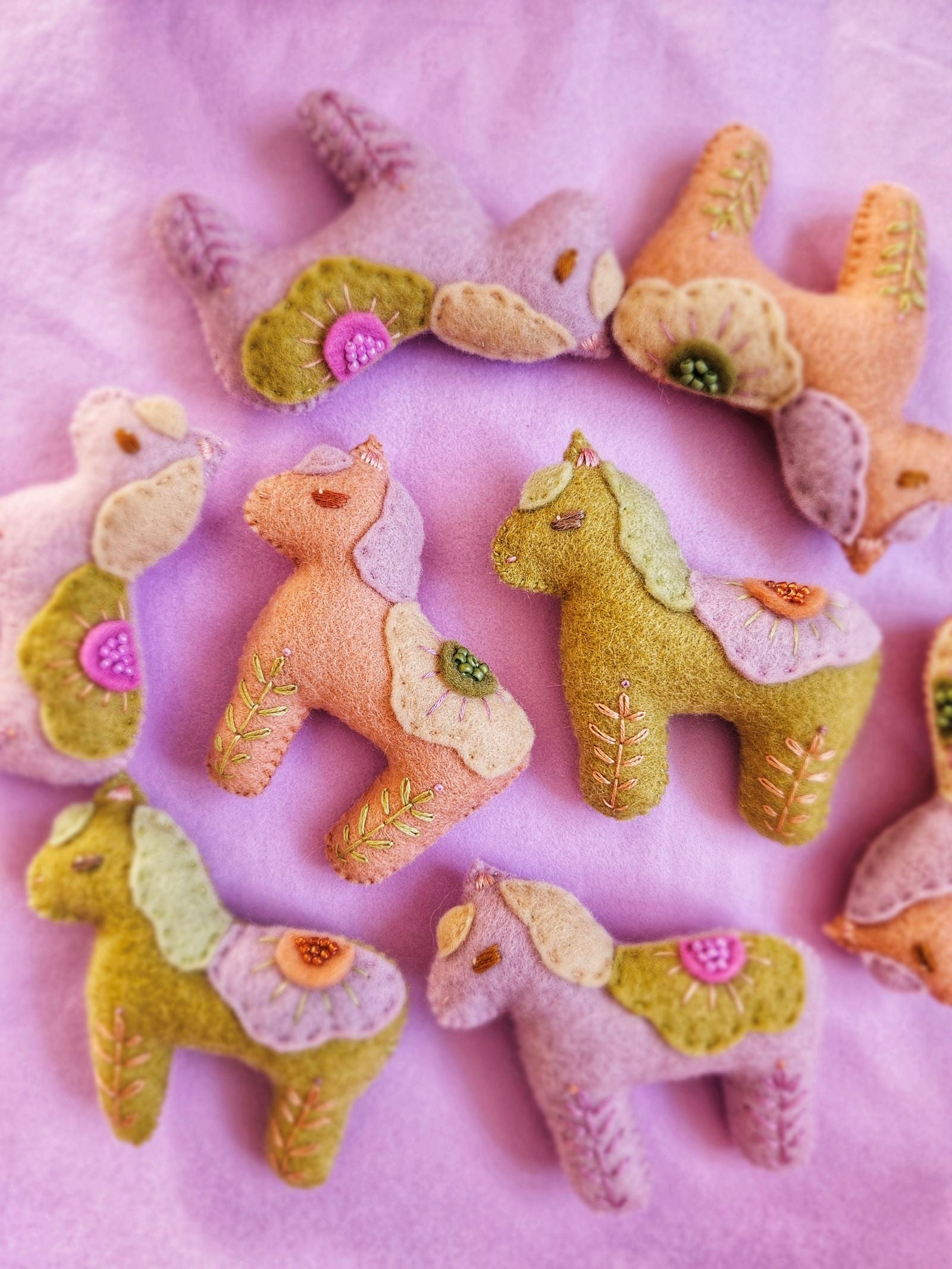 Felt animal toys arranged in a circle on a pink background