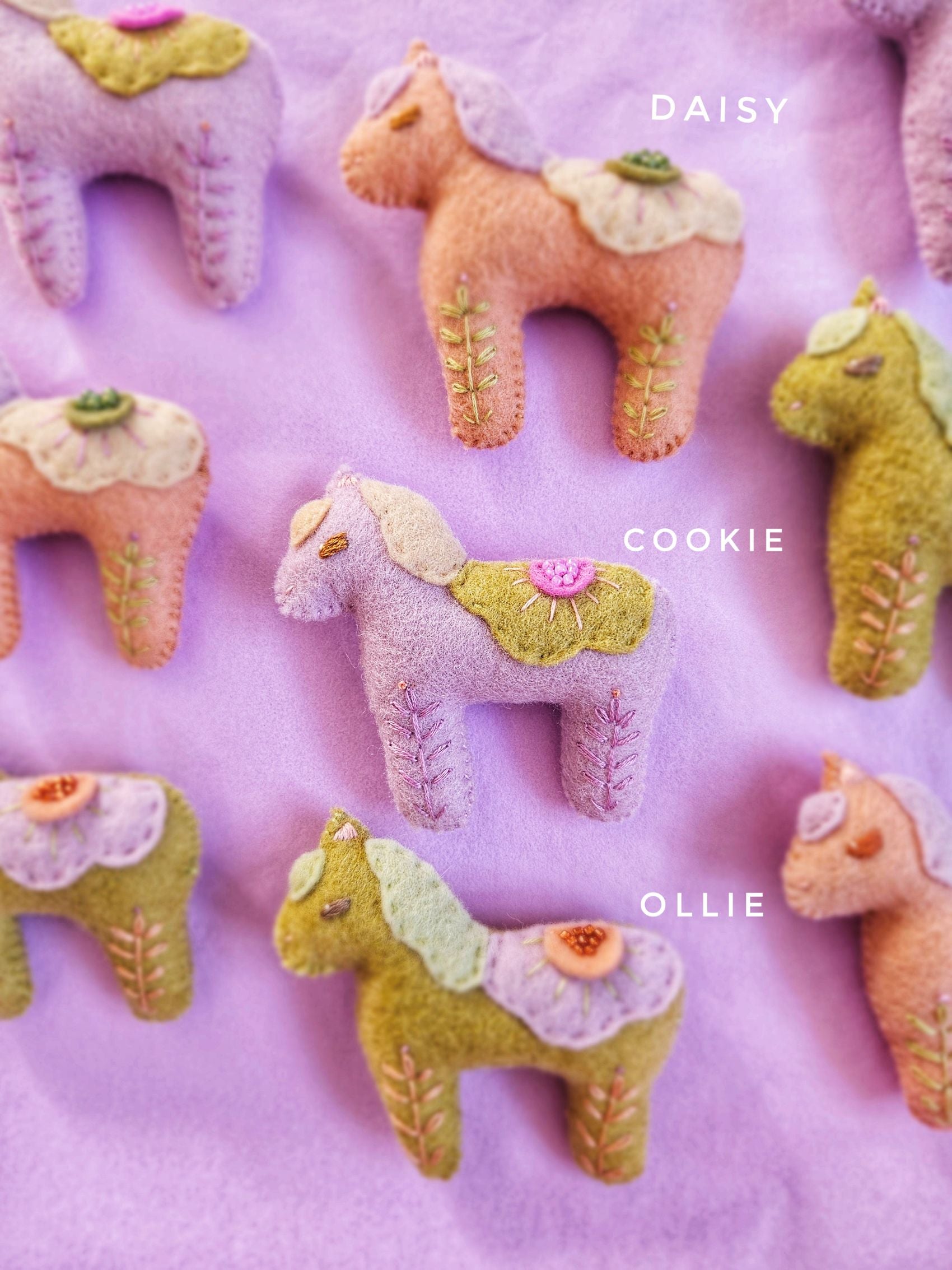 Felt horse toys labeled 'Daisy', 'Cookie', and 'Ollie' on a pink background