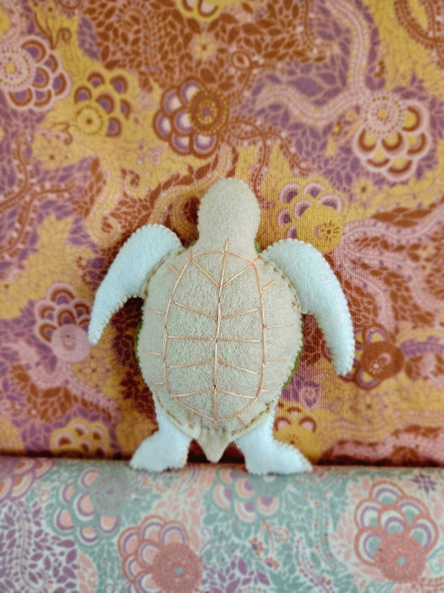 Stuffed turtle toy on a patterned fabric background