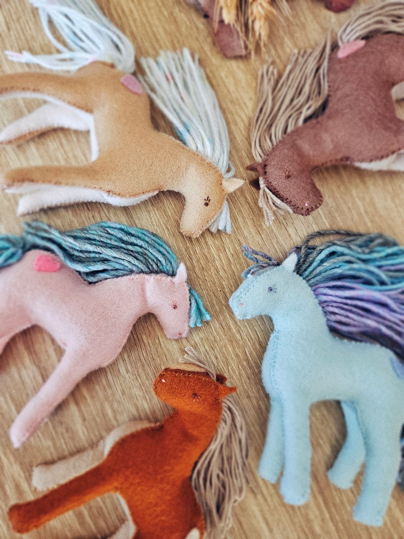 Collection of colorful felt horse toys on a wooden surface