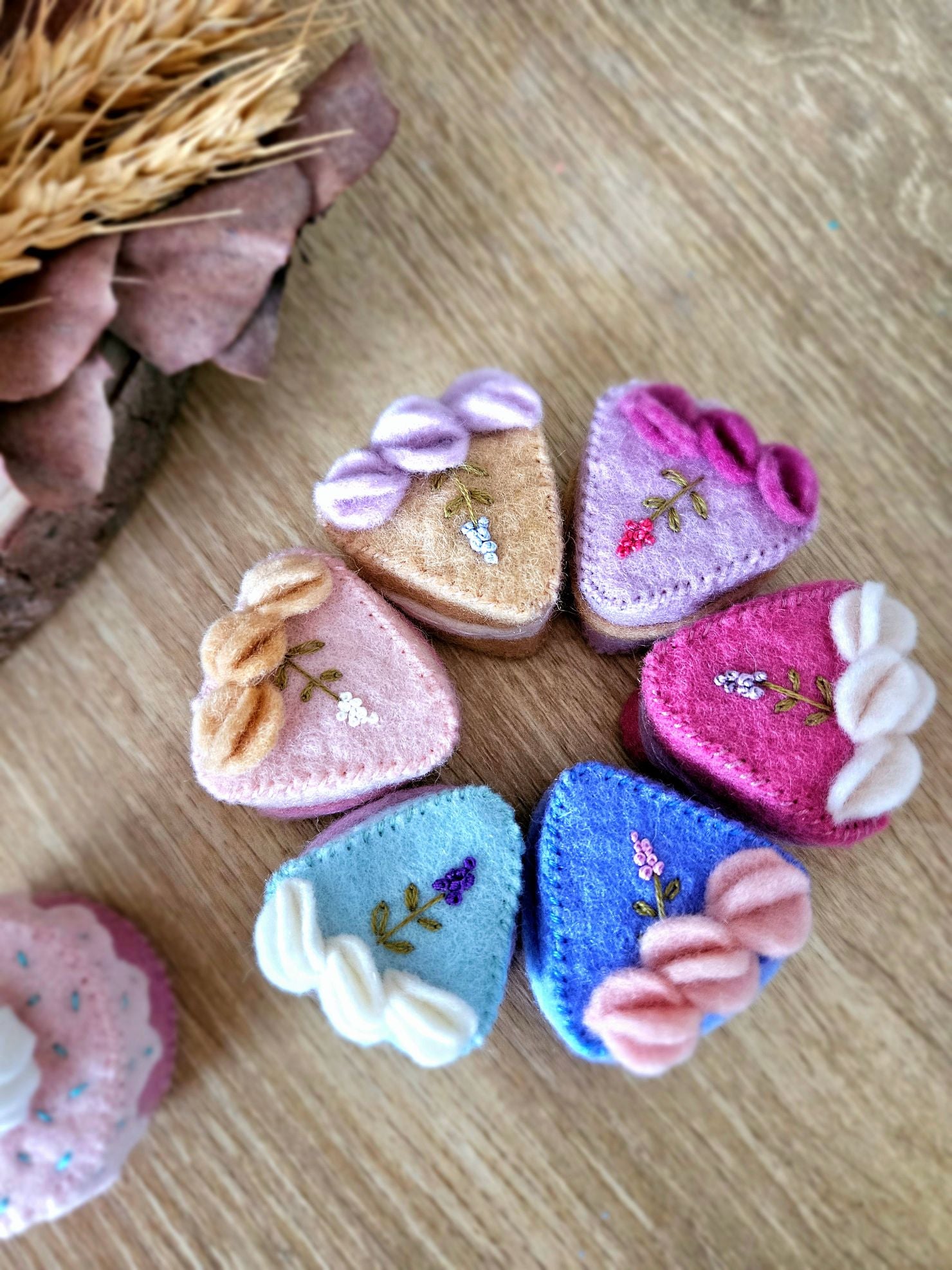 Colorful embroidered lavender themed wool felt cake slices on a wooden surface
