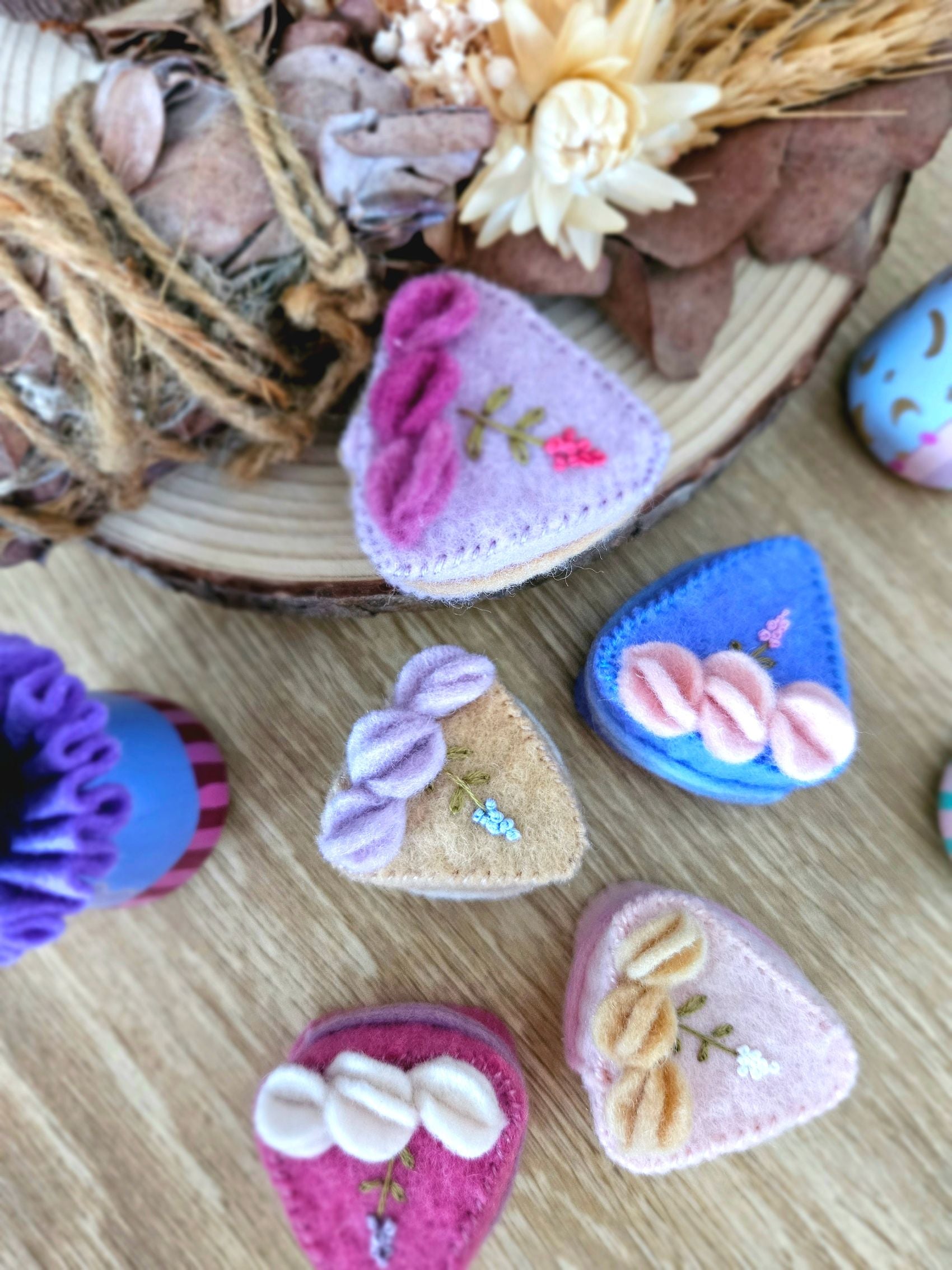 Wool felt handmade cake sliced, with lavender embroidery on a wooden surface with natural elements in the background