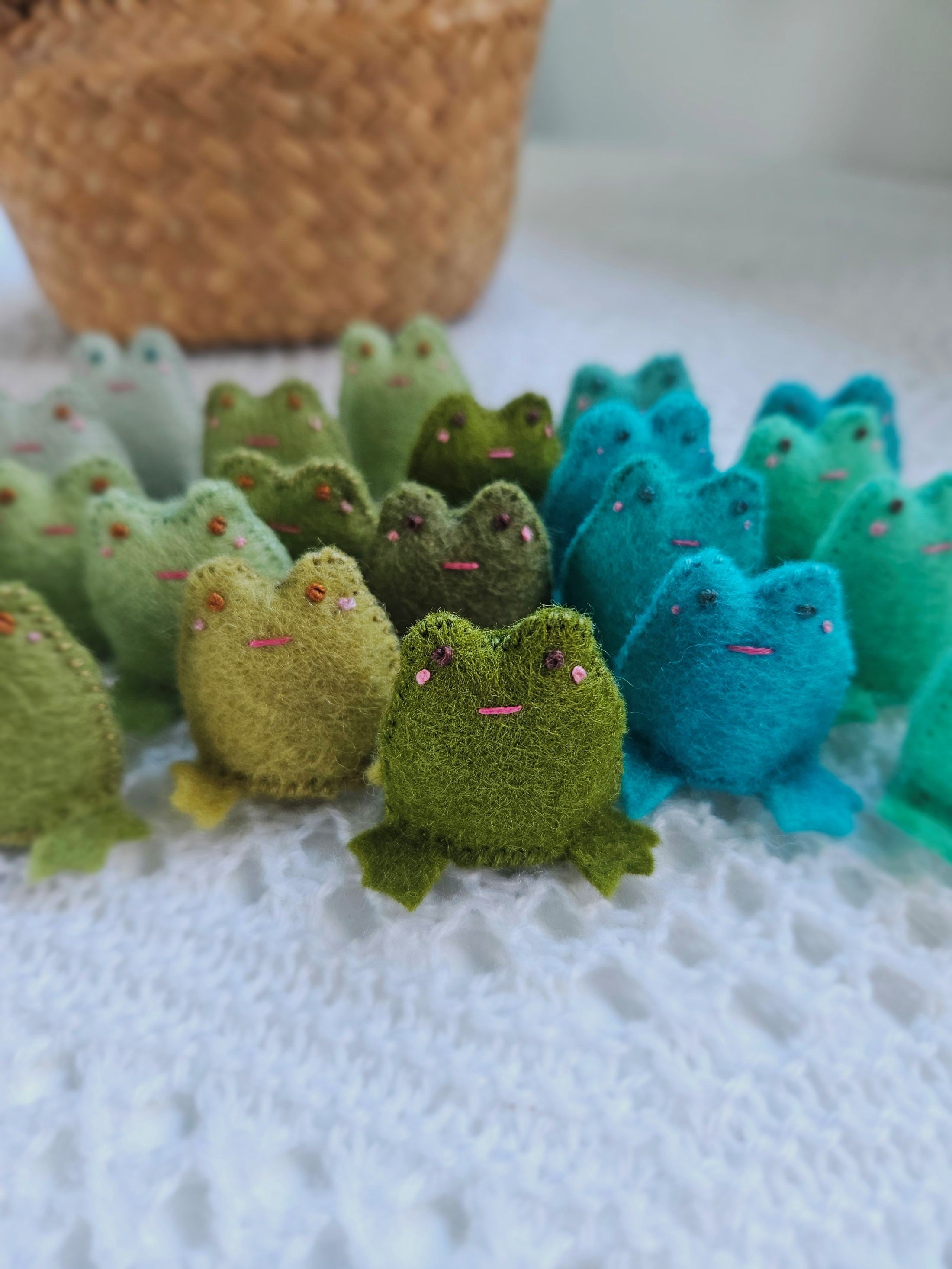 Row of knitted frogs in various colors on a textured surface