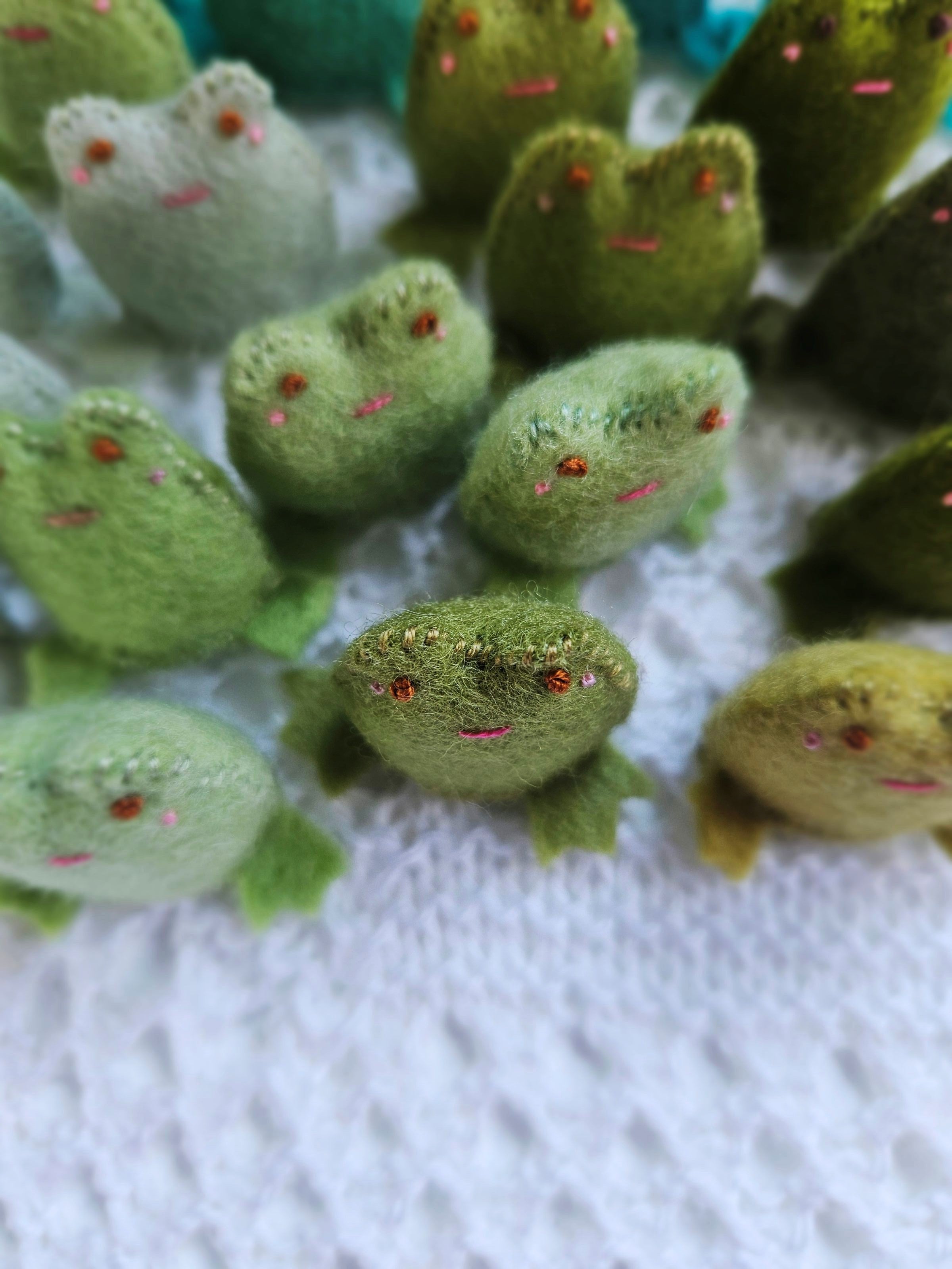 Close-up of green plush toy frogs on a textured white surface
