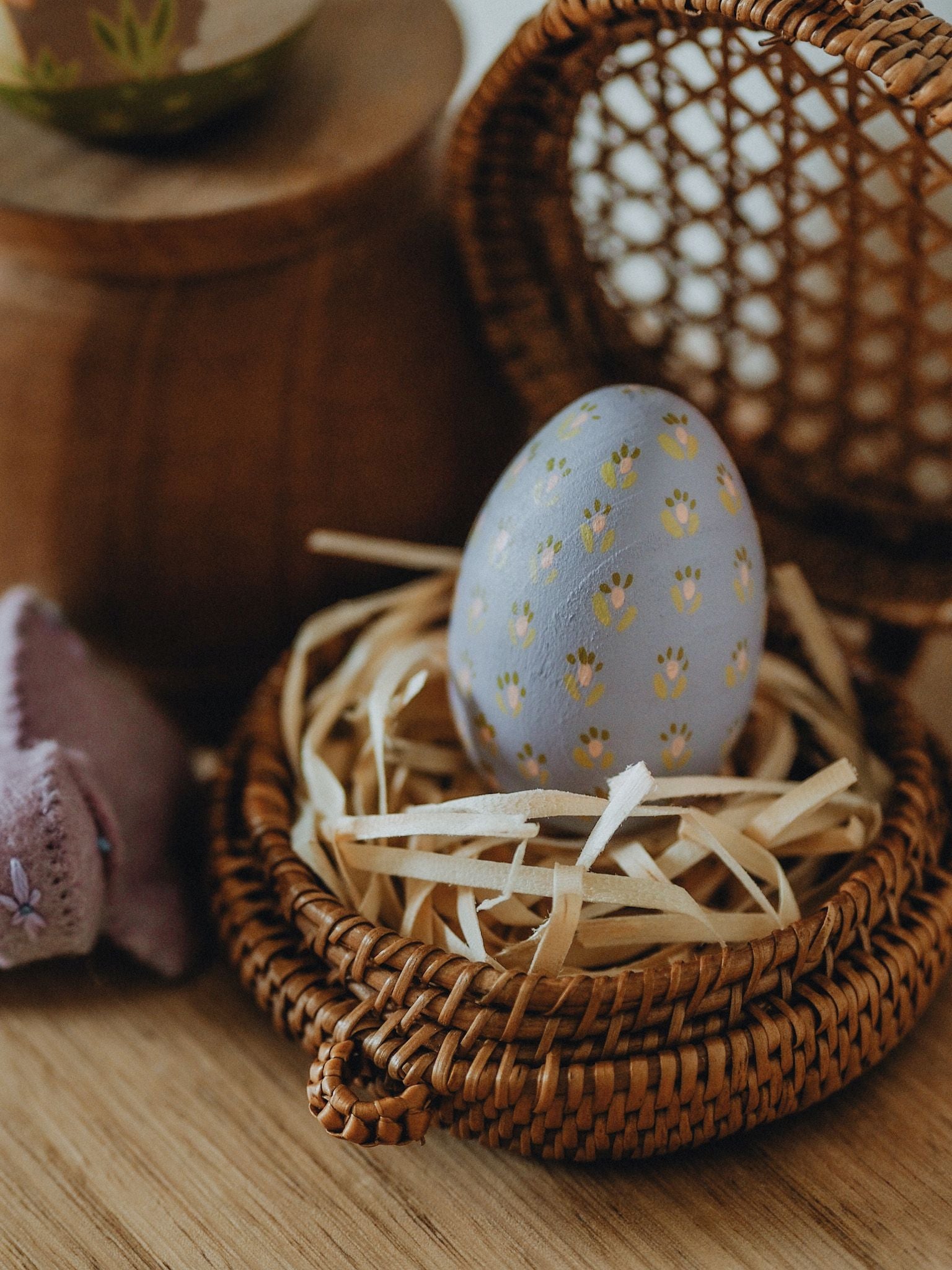 Decorative wooden egg with floral prints in a wicker basket 